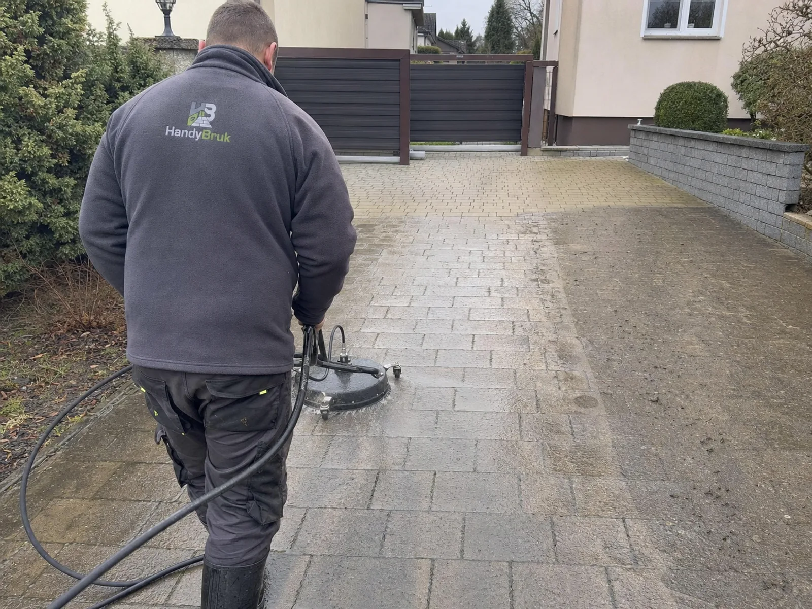 Pracownik HandyBruk myje kostkę urządzeniem ciśnieniowym